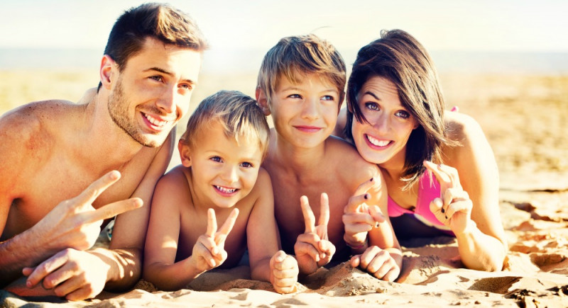 happy family posing for a souvenir photo on the beach front of the sea